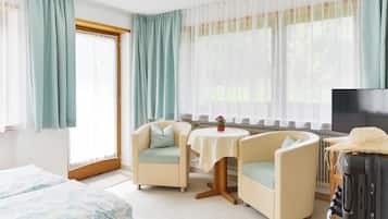 Camera d'albergo con due poltrone, un tavolino, una televisione e un letto.