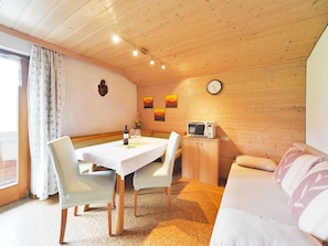 A cozy room with a dining table, chairs, a microwave, a sofa, and a clock on the wall. - Apartment Toblermann - Pension Oberhauser (Schoppernau)