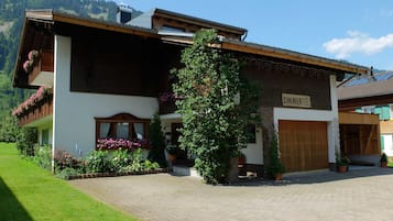 Un edificio a due piani con facciata in legno e un cartello con su scritto 'ZIMMER', affiancato da un vialetto lastricato.
