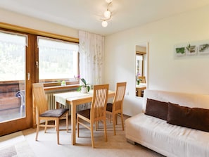 A cozy room with a dining table, chairs, a sofa, and a window with curtains. - Apartment Toblermann - Pension Oberhauser (Schoppernau)