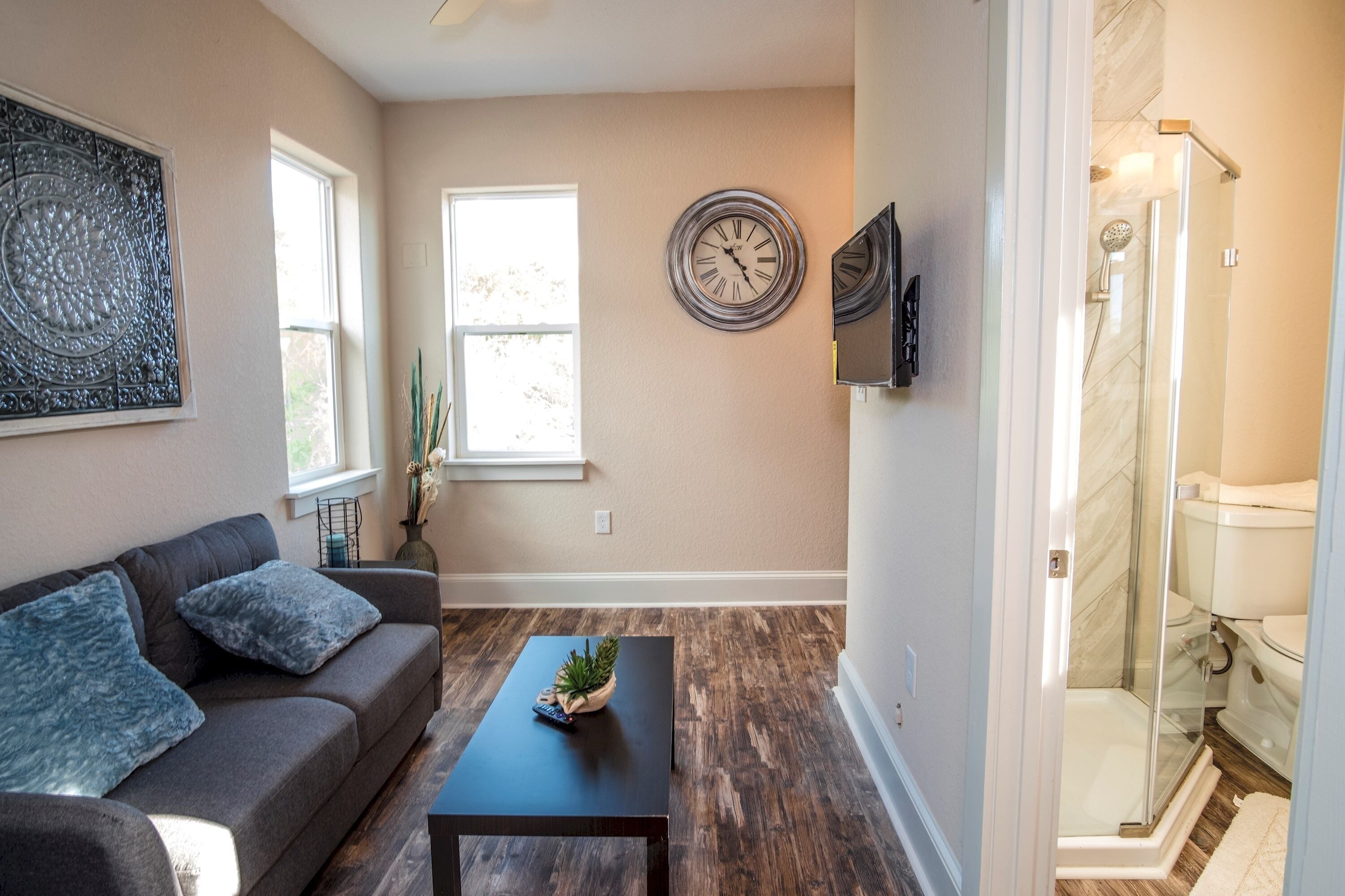 A living room with a sofa, coffee table, and a clock on the wall.