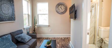 A living room with a sofa, coffee table, and a clock on the wall.