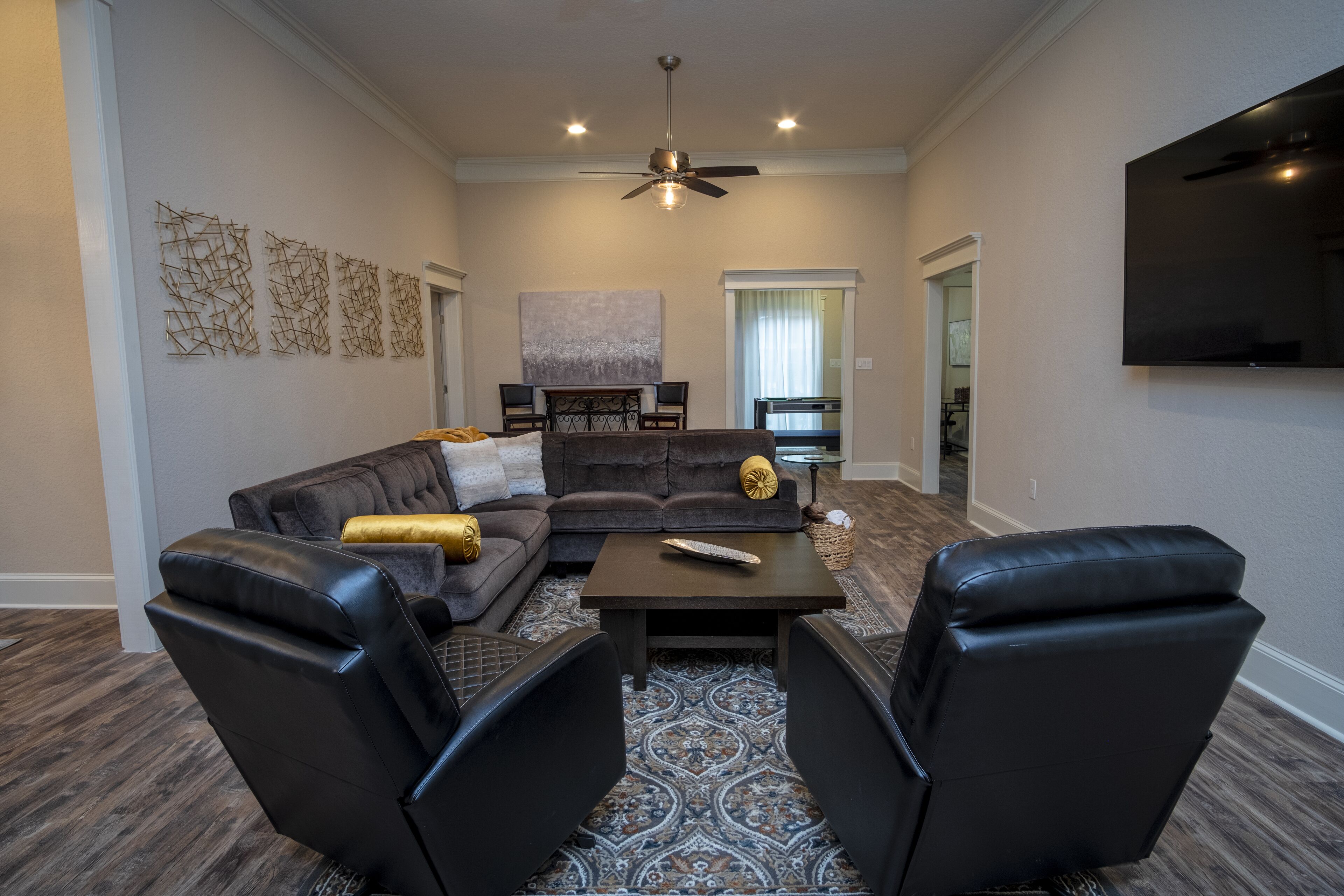 A living room with a sectional sofa, two leather chairs, a coffee table, and a flat-screen TV.