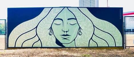 A large outdoor mural with a woman's face, surrounded by a fence.