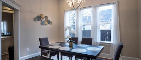 A dining area with a dark wooden table, six chairs, a bench, and a chandelier.
