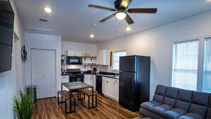 A modern kitchen with white cabinets, a black refrigerator, and a dining area with a wooden table and benches. - Downtown View Cozy 2br/1ba Home Sleeps 8 (San Antonio)