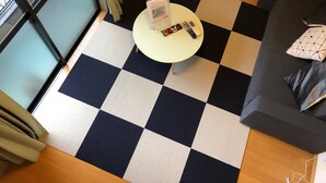 A checkered floor with a round table in the center, a sofa with cushions, and a television on a stand. - Espoir (Kumamoto)