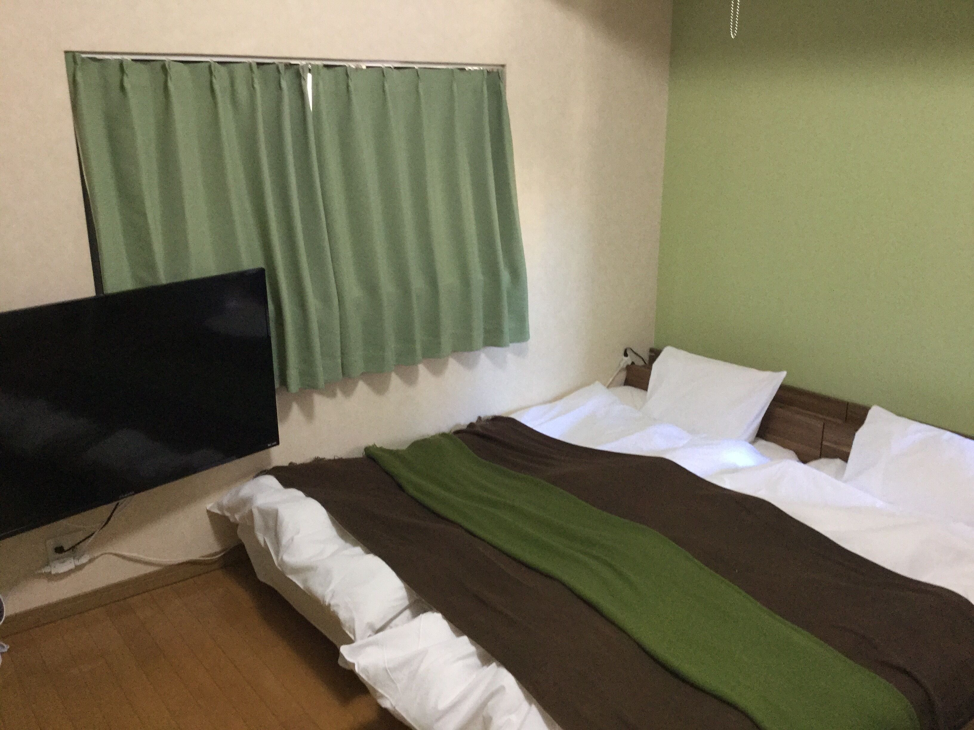 Una habitación de hotel con cama, televisión y cortina.