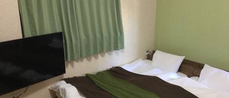 Une chambre d’hôtel avec un lit, une télévision et un rideau.
