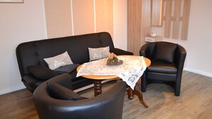 A living room with a black sofa, a round wooden coffee table, and a black armchair. - Wendt apartment, Germany (Insel Poel)