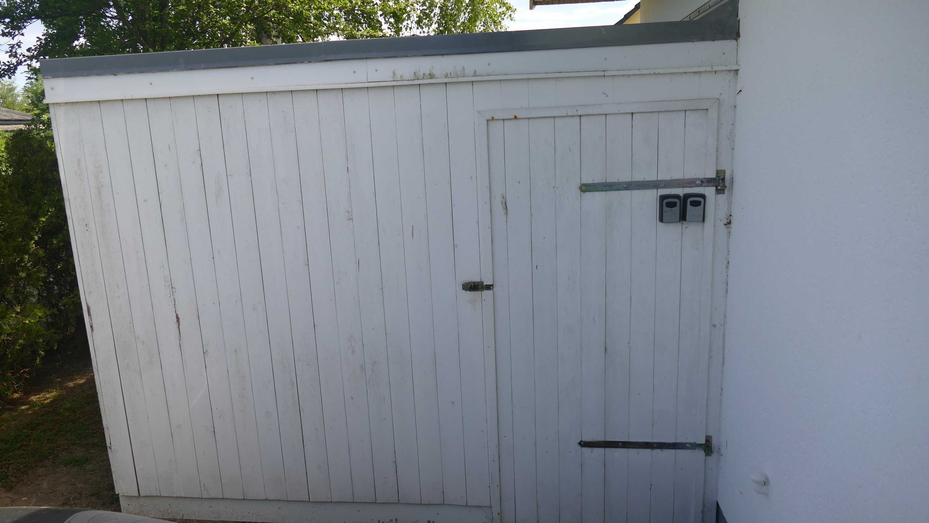 Une porte de garage blanche, dotée d’une poignée en métal et de deux petits objets rectangulaires fixés à sa surface.
