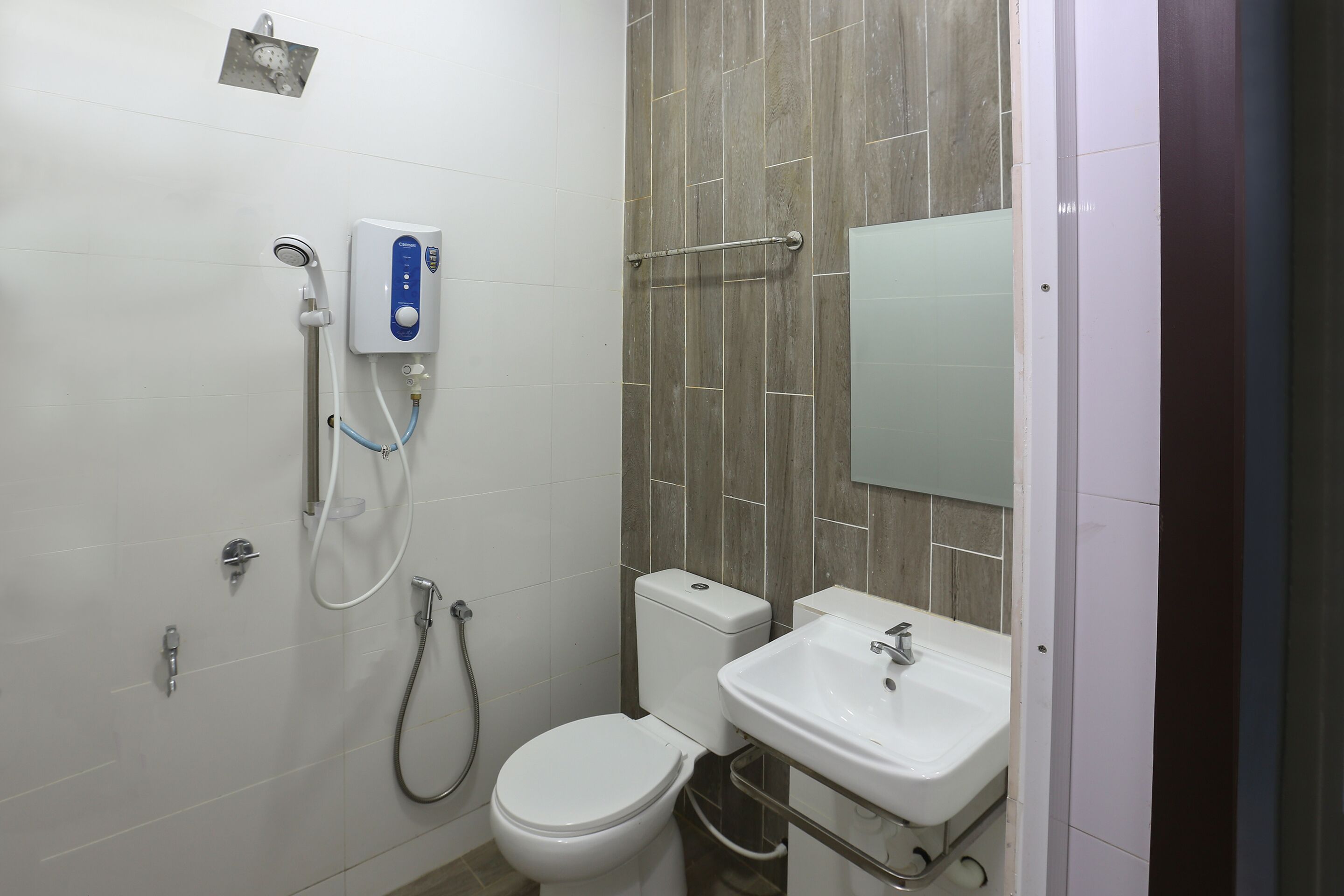 A bathroom with a toilet, a sink, a shower, and a hand dryer.