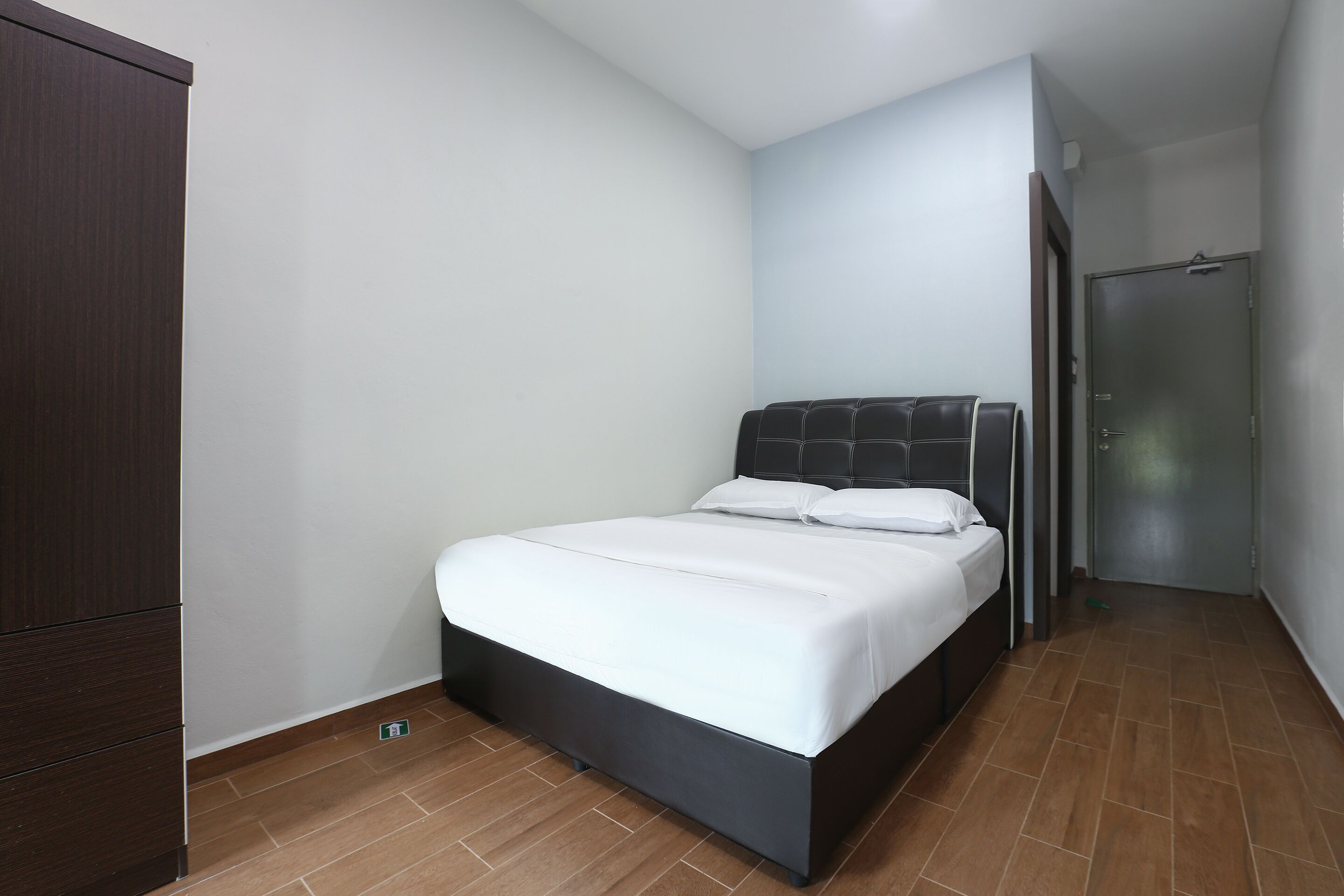 A bedroom with a bed, a wardrobe, and a door.