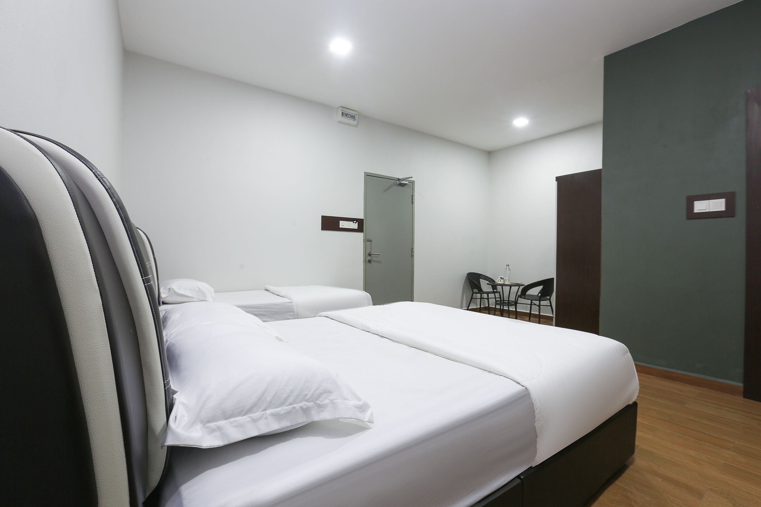 A hotel room with two beds, a desk, and a chair.