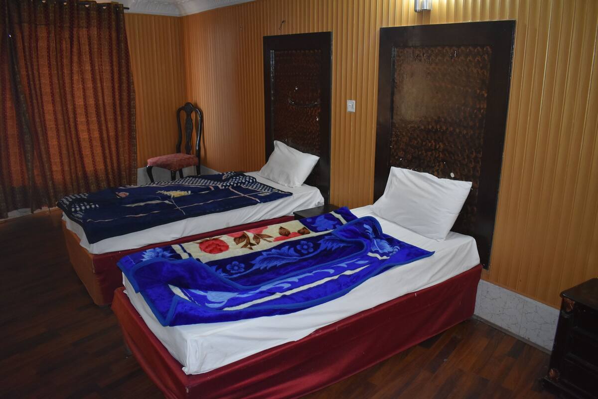 A hotel room with two beds, wooden paneling on the walls, and a red bedspread.