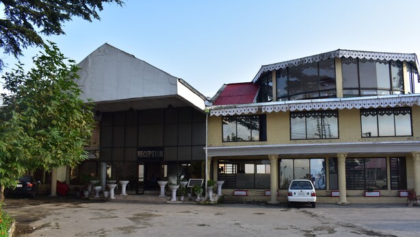 A building with a reception area, large windows, and a parking lot. - Grand Heights Hotel (Murree)
