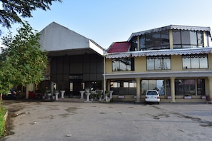 A building with a reception area, large windows, and a parking lot. - Grand Heights Hotel (Murree)