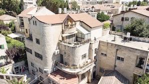 A multi-story building with a stone facade, balconies with flower boxes, and a rooftop terrace. - Luxury Triplex In Jerusalem Center (Jerusalem)