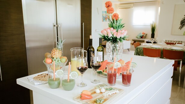 A kitchen counter with a variety of food items, drinks, and a decorative vase with flowers. - Luxury Triplex In Jerusalem Center (Jerusalem)