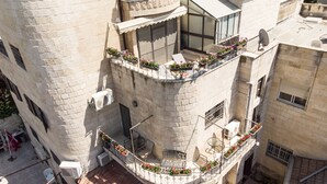 A multi-story building with a balcony featuring potted plants and outdoor seating. - Luxury Triplex In Jerusalem Center (Jerusalem)