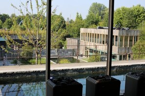 A modern building with large windows and a view of a water body. - Waer Waters spa Hotel (Dilbeek)