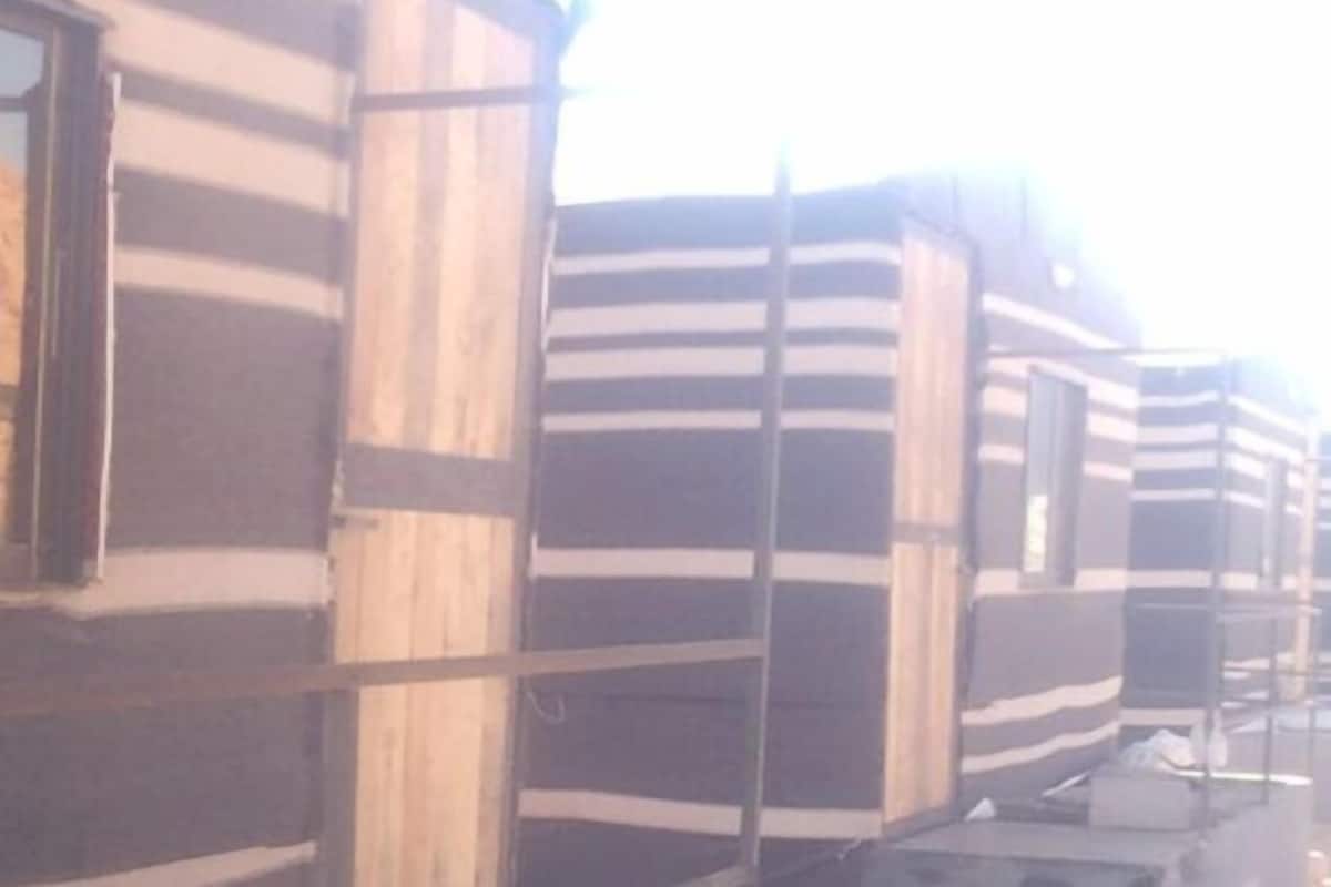 A row of cabins with a striped exterior, a window on the left, and a metal railing.