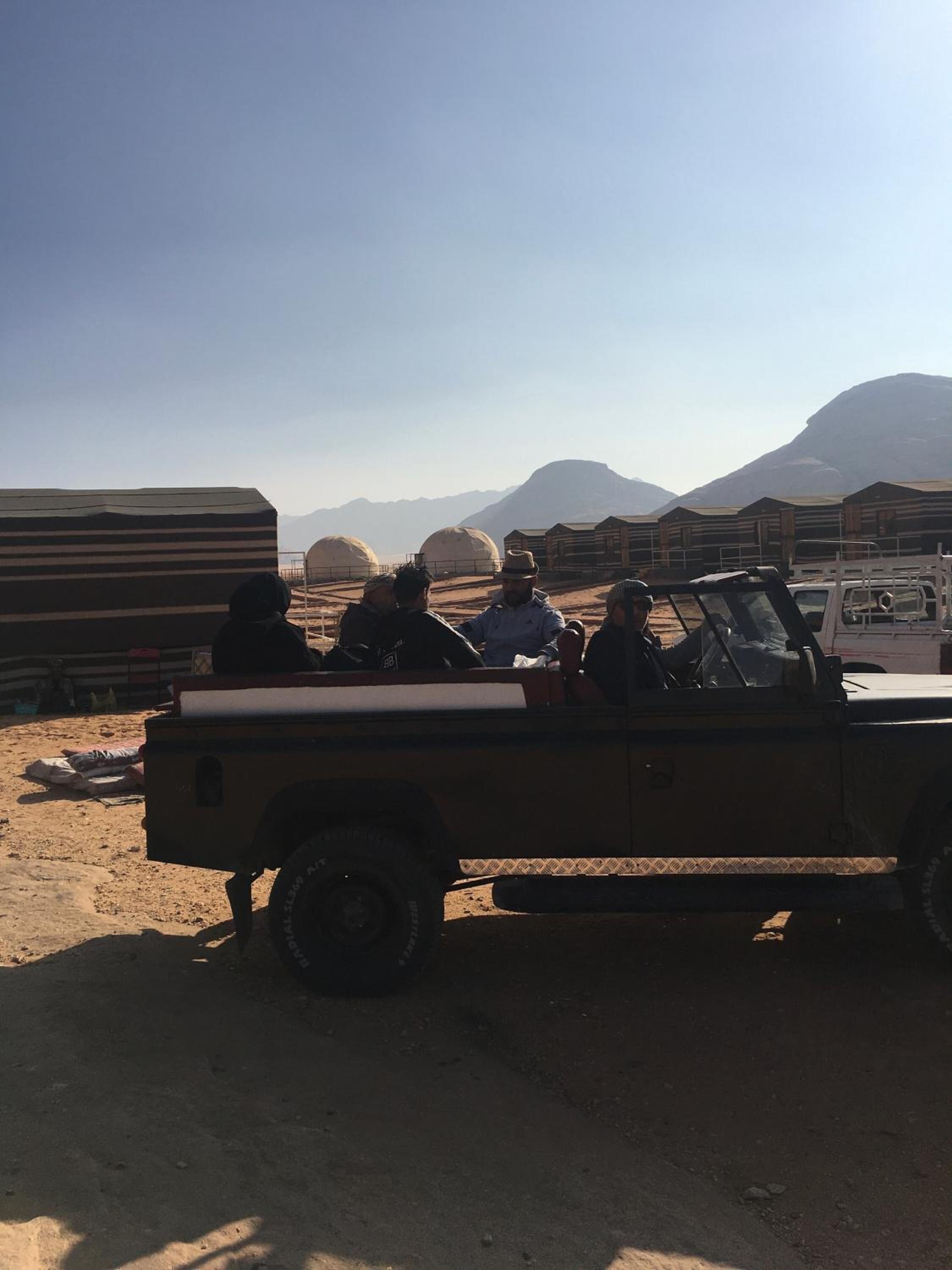 A desert scene with a vehicle and tents.