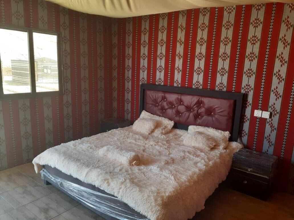 Un dormitorio con una cama grande, cabecera con diseño floral y papel tapiz estampado.