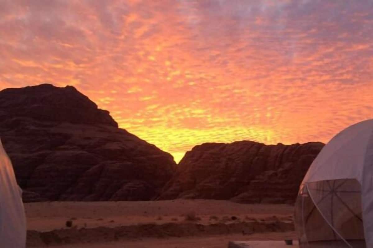 A desert landscape at sunset with tents in the foreground.