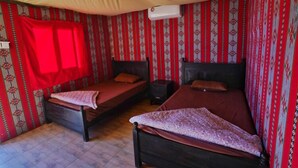 A room with two beds, a nightstand, and a red curtain. - Oryx camp (Wadi Rum)