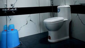 Et badeværelse med toilet, bruser og to blå dispensere på gulvet.