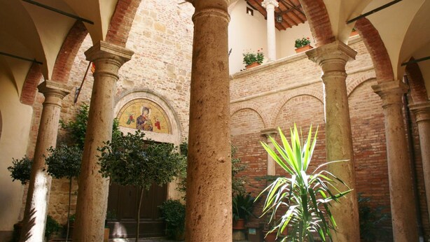 An interior courtyard with stone columns, arches, and a mosaic.