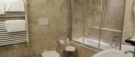 A bathroom with a shower, toilet, bidet, and sink.