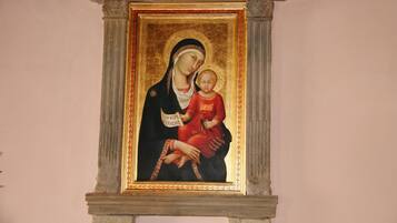 Un tableau religieux encadré, doté d’un cadre doré, fixé sur une structure en pierre.