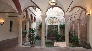An interior courtyard with arches, columns, and potted plants.