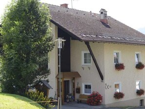 A building with a sloped roof, a porch, and flower boxes. - Double room 4 - Erd's Hoimatle (Jungholz)