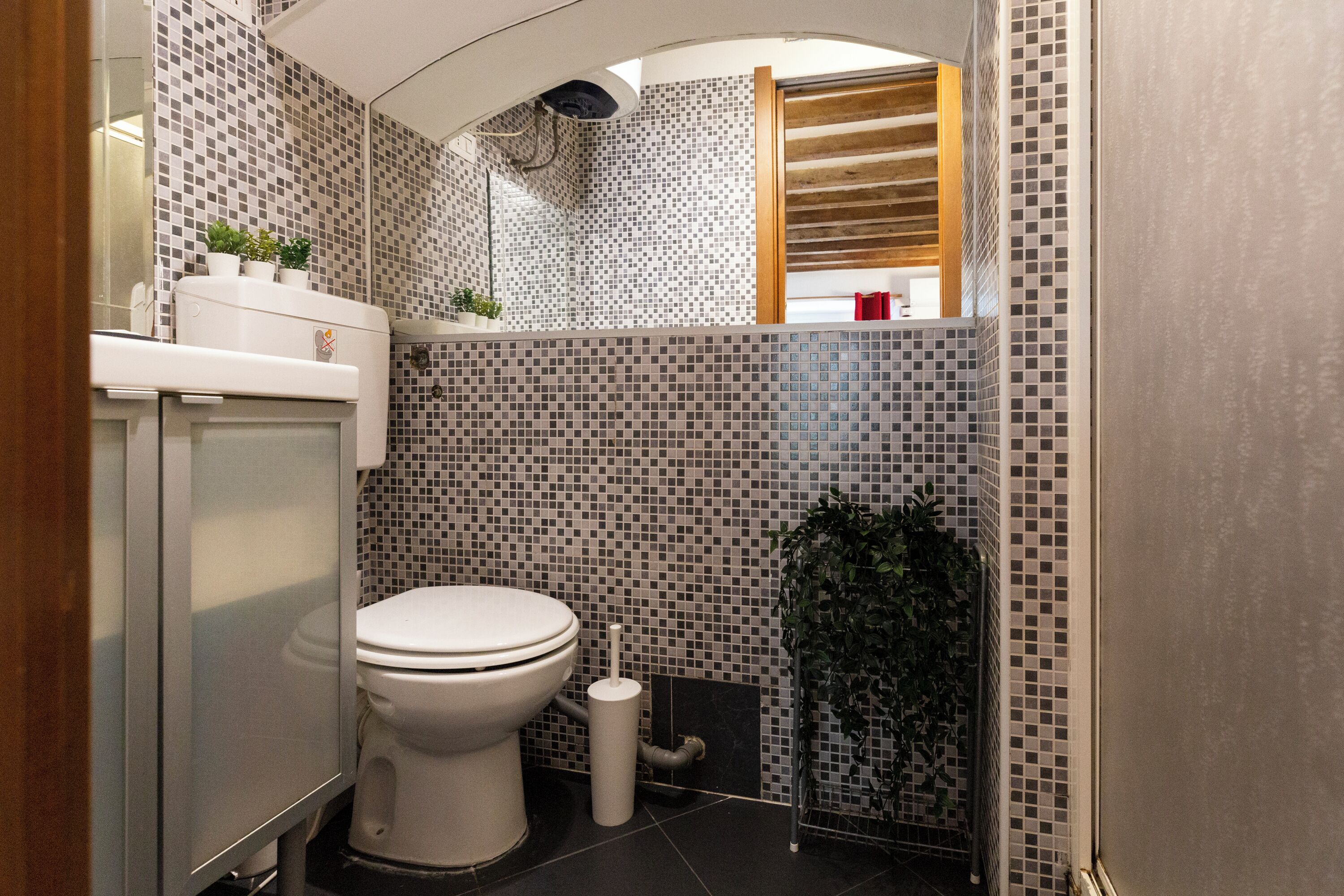 A compact bathroom with a toilet, a sink, and a mirror.