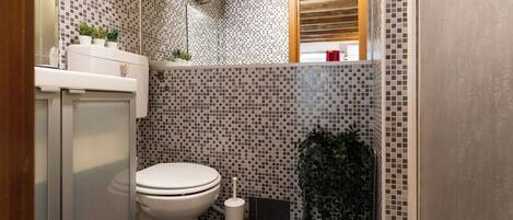 A compact bathroom with a toilet, a sink, and a mirror.