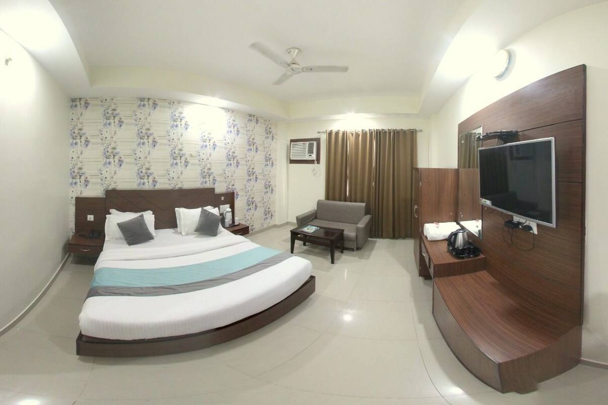 A hotel room with a bed, a TV, a desk, a chair, and a ceiling fan.