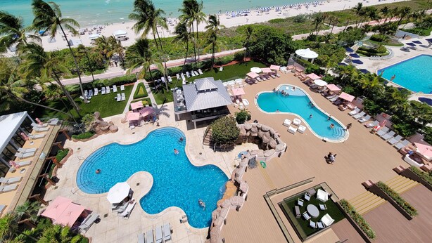A resort with multiple swimming pools, sun loungers, and a beach area.