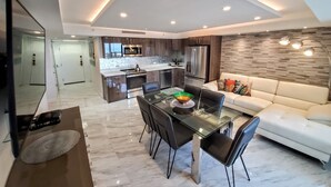 A modern kitchen with dark wood cabinets, stainless steel appliances, and a glass dining table.