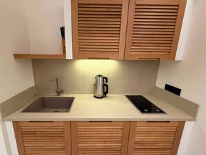 A compact kitchen with a double sink, a kettle, and wooden cabinets.