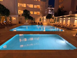A swimming pool with lounge chairs and umbrellas, surrounded by a building with multiple floors and balconies. - Pasahan Apart (Marmaris)