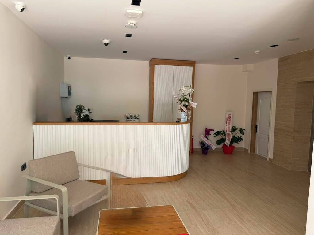 Un espace d’accueil comprenant un comptoir de réception, un coin salon et une plante en pot.