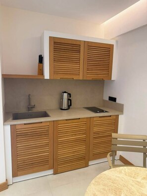 A compact kitchen with a sink, a coffee maker, and wooden cabinets. - Pasahan Apart (Marmaris)