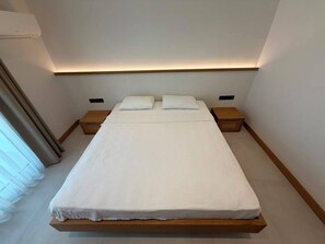 A modern bedroom with a single bed, bedside tables, and a built-in headboard. - Pasahan Apart (Marmaris)