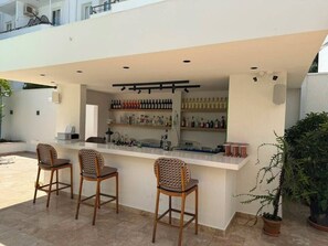 An outdoor bar area with a counter, bar stools, and shelves of bottles. - Pasahan Apart (Marmaris)