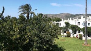 Un bâtiment blanc, doté d’un toit plat, entouré de verdure et surplombé d’un ciel dégagé.