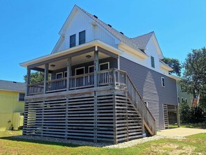 Une maison à deux étages avec un porche couvert et une terrasse en bois.
