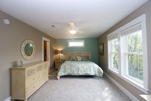 A bedroom with a bed, dresser, ceiling fan, and large windows. - Nags Head OCEANSIDE! 3 Bedroom 4 Bath Home! Beautiful 5 Star Property! (Nags Head)